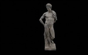Antike Statue eines männlichen Körpers in natürlicher Pose vor schwarzem Hintergrund.