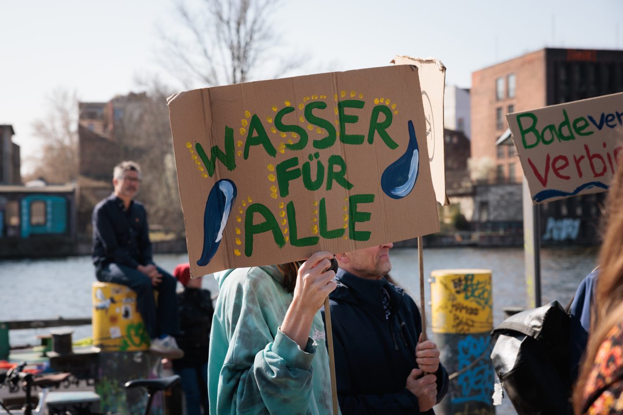 Aktivist*innen mit Protestschildern an der Spree