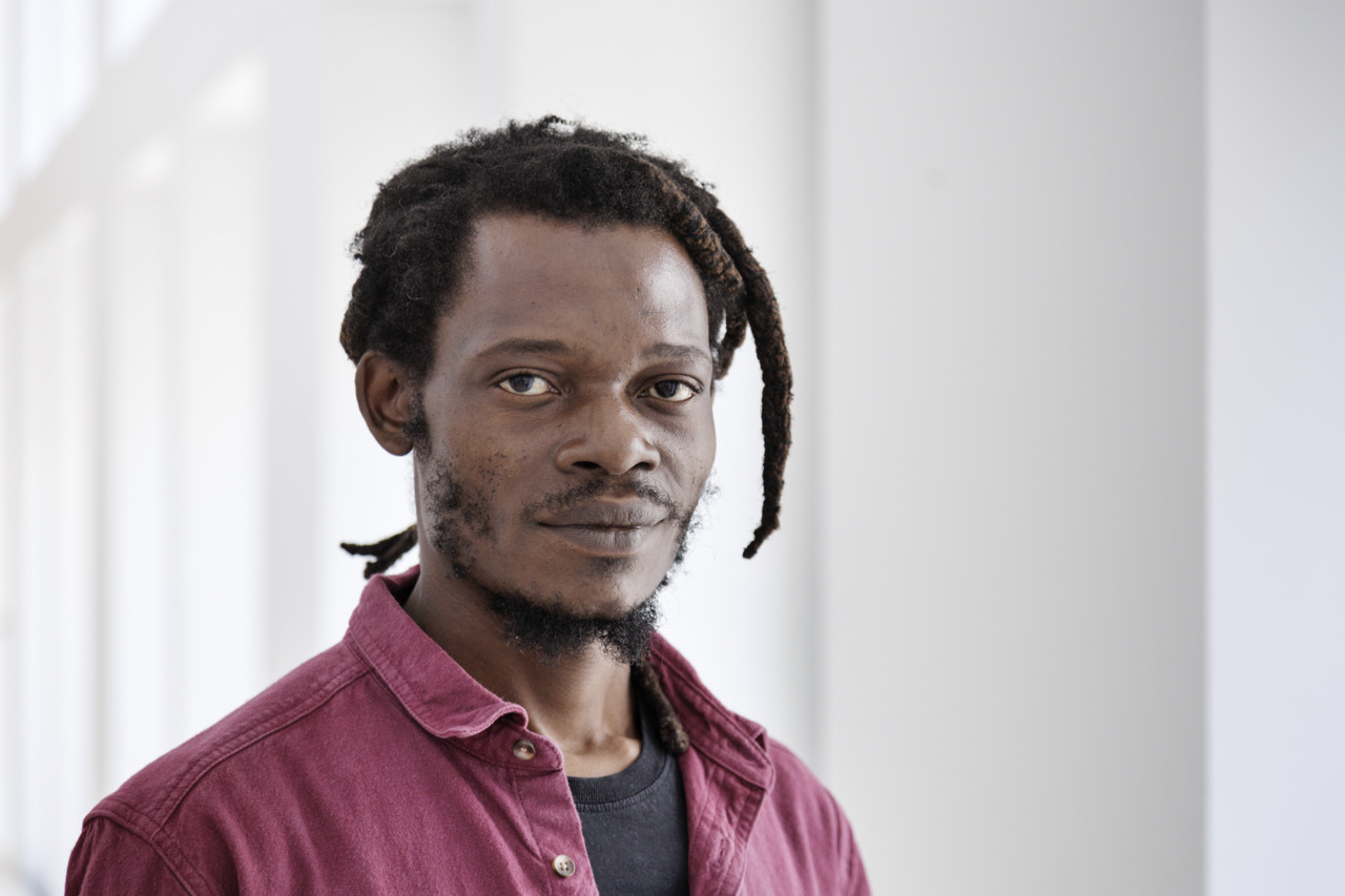 Porträt eines Mannes mit Dreadlocks in einem modernen Raum mit natürlichem Licht.