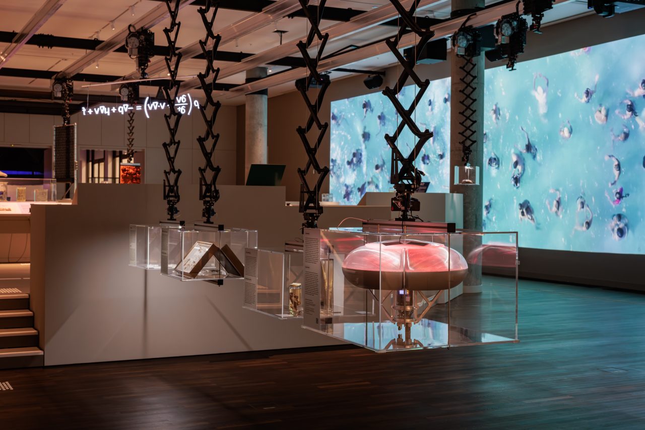 Interactive exhibition with floating objects and digital displays presenting scientific concepts.