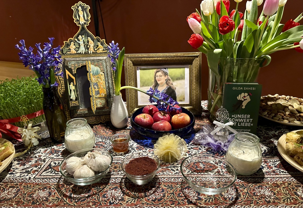 Ein Tisch geschmückt mit Blumen, Obst, traditionellen Gerichten und Bildern für ein festliches Ritual oder Feier.