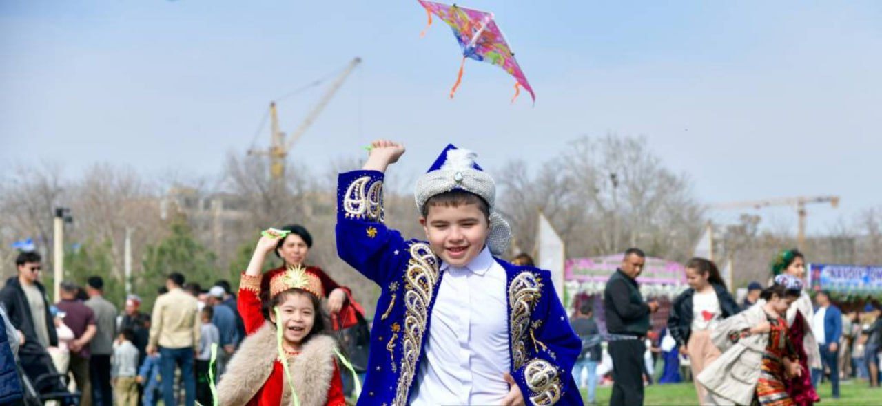 Children in traditional costumes celebrate while flying kites and laughing joyfully.