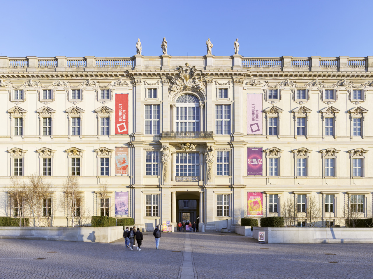Historical facade of the Humboldt Forum in Berlin with art installations and visitors in the foreground.