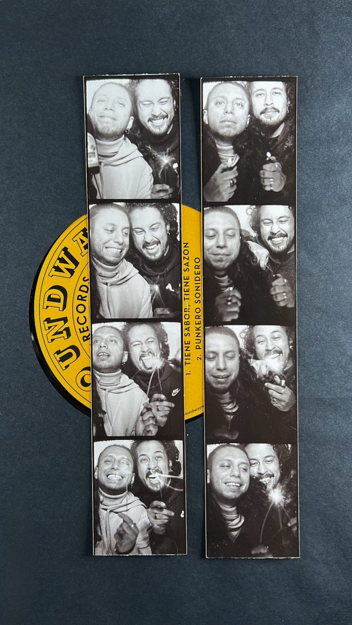 Two men in black-and-white portraits smile while holding lighters, surrounded by a vinyl record.