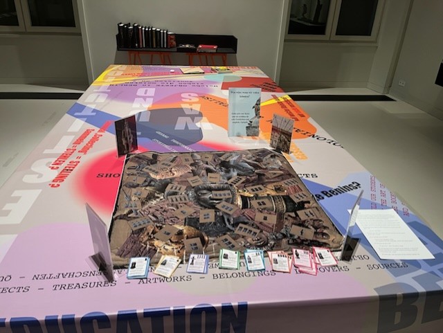 Interactive exhibition featuring a central table with an image and info cards, surrounded by colorful design elements.