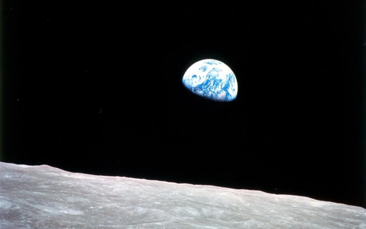 Earth is visible in the background above the moon's surface against a black space backdrop.