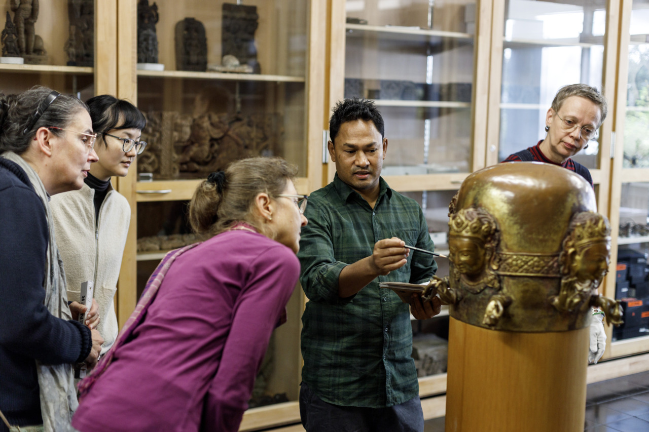 Group discussion about an art restoration in a museum, focusing on a sculpture and its details.