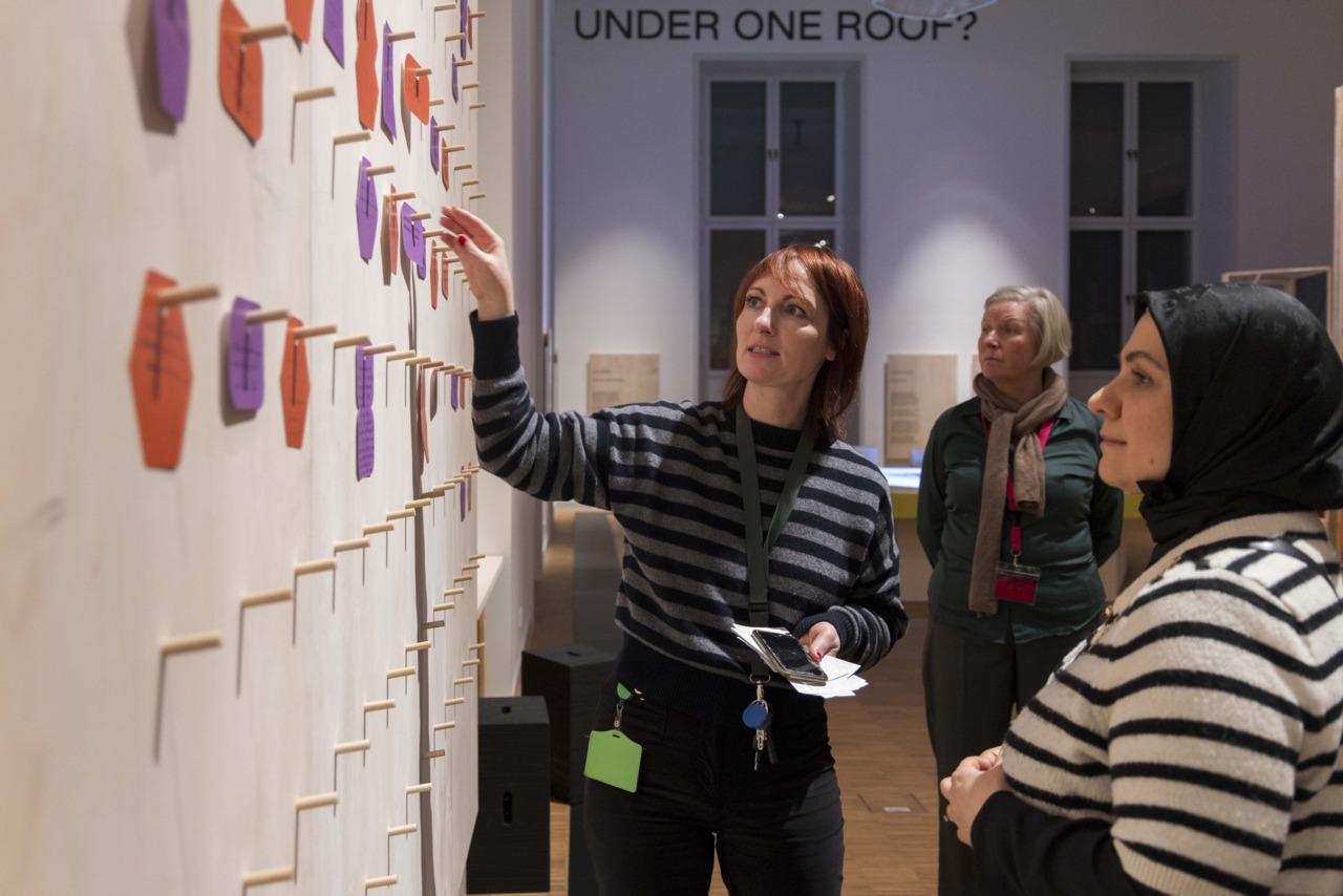 Visitors explore an interactive wall installation with colorful cards in an exhibition space.