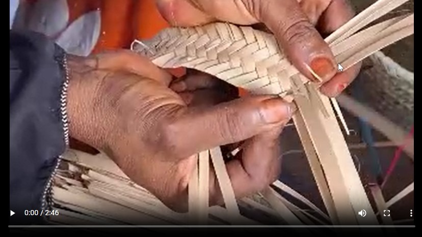 Hands carefully weave materials to create a braided object.